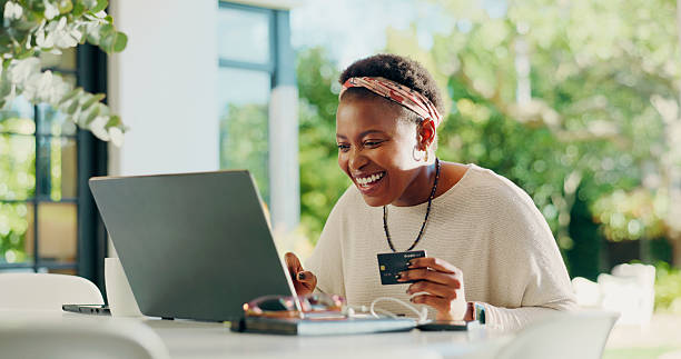 Black woman, laptop and credit card for payment in home with booking, typing and remote work on web. Person, virtual assistant and purchase for online shopping, ecommerce or easy transaction in house